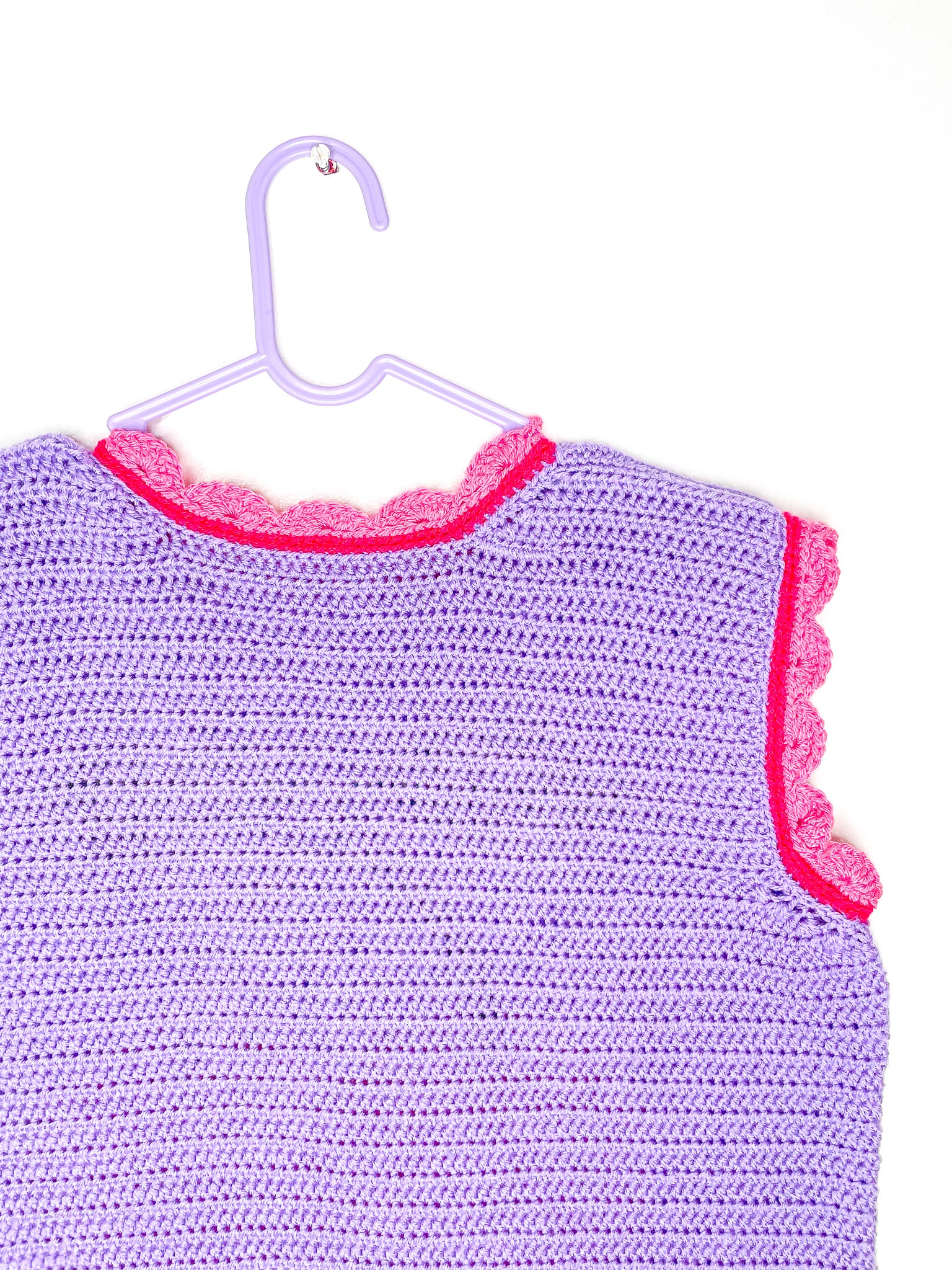 Close back view of a lilac vest top with pink edges showing the crochet stitches.