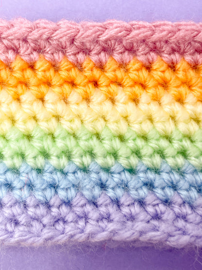 Close up of a crochet headband in pastel rainbow colours with the stitch details.