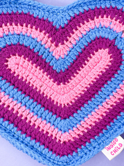 Close view of a crochet heart bag with a bisexual flag rainbow on the front, showing the crochet stitches.