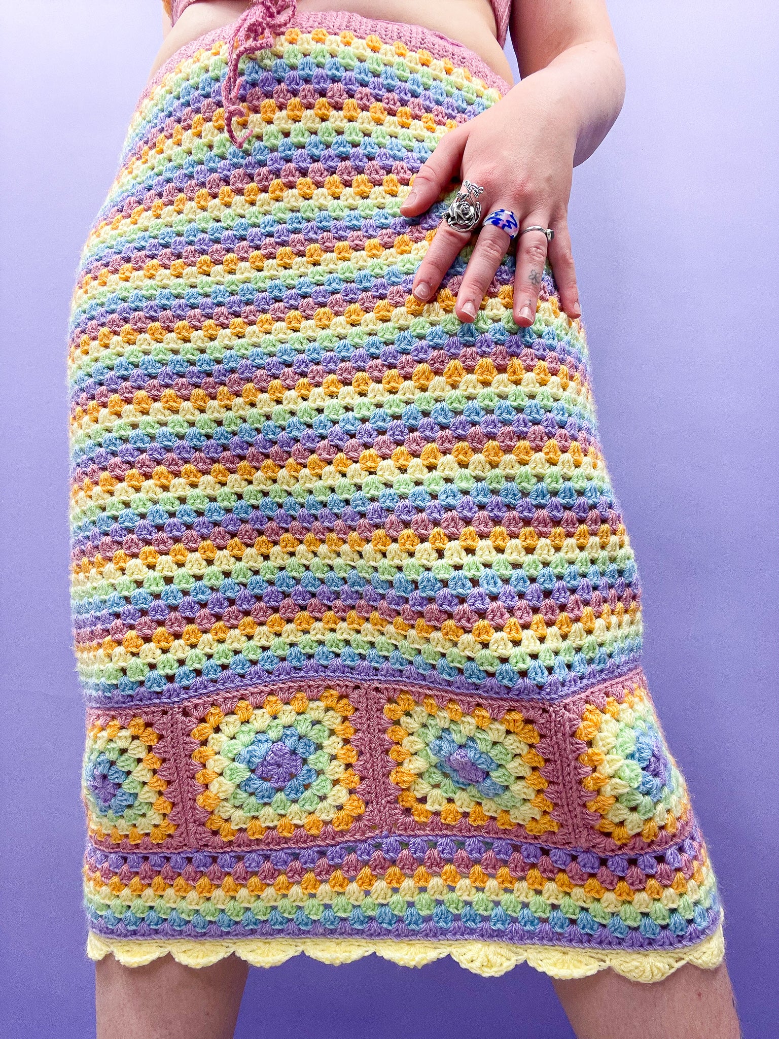 Close up of woman wearing a pastel rainbow midi skirt with a granny square design at the bottom and yellow frilled edges.