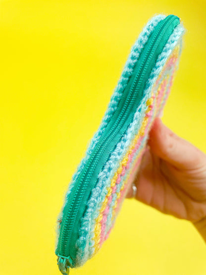 A hand holding a coin purse showing the zipper side.