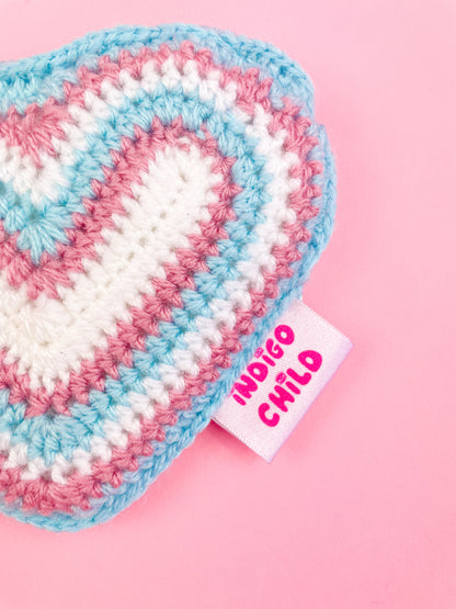 Close up of a crochet coin purse shaped like a heart and highlighting the 'Indigo Child' outer tag.