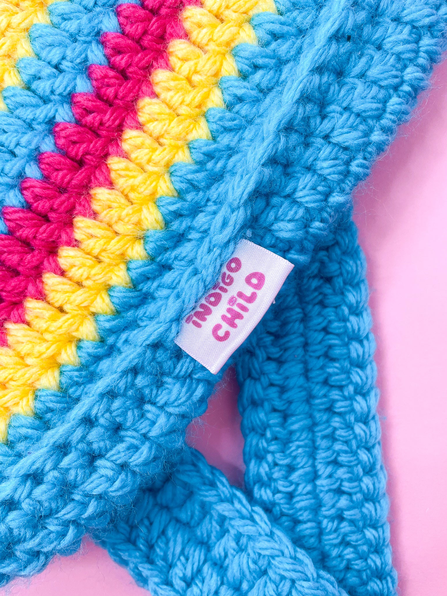 Close view of a crochet bag in blue, yellow and pink with an Indigo Child label sewn in the side.