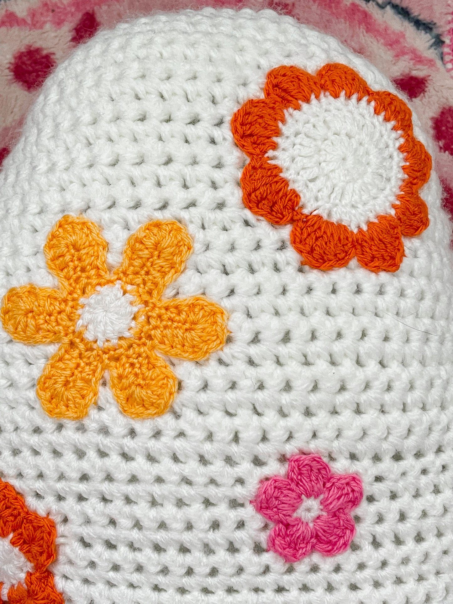 Back close view of a white pillow with appliqué flowers attached showing the crochet details.