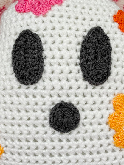 Close view of a handmade ghost face with crochet appliqué pieces for the eyes and mouth attached to the base.